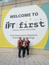 Three female students in front of IFT First conference sign