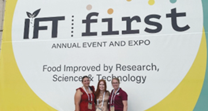 Three female students in front of IFT First conference sign