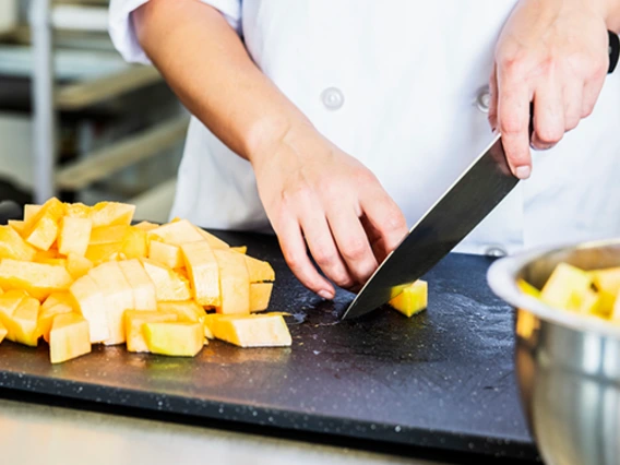 Hands of person cutting pieces of cantaloupe