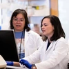 Zelieann Craig looking at a computer monitor in a lab while wearing a lab coat